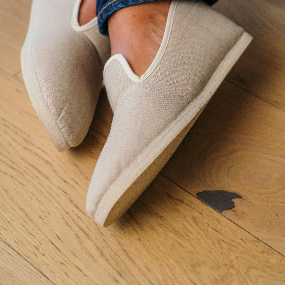 Les charentaises propres Naturel, portées jambes croisées sur parquet